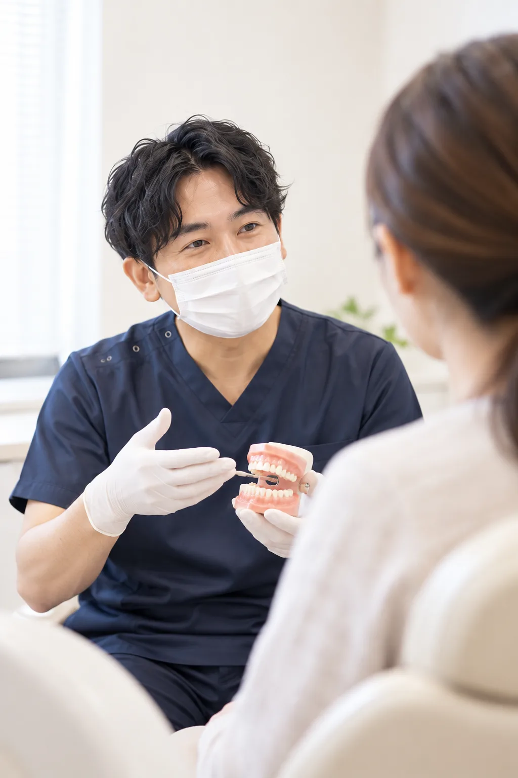 歯科医師が大人の受診者と歯の模型を見ながら話す場面